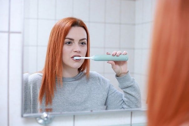 kobieta myjąca zęby szczoteczką elektryczną