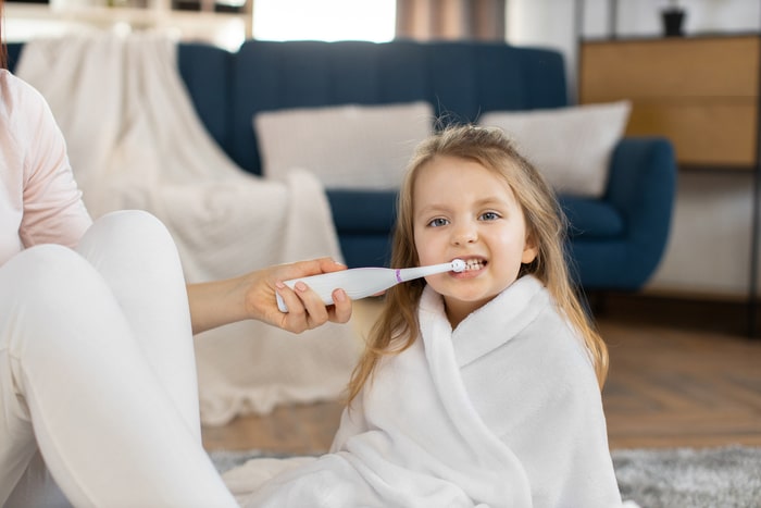 Dziewczynka w czasie mycia zębów szczoteczką elektryczną