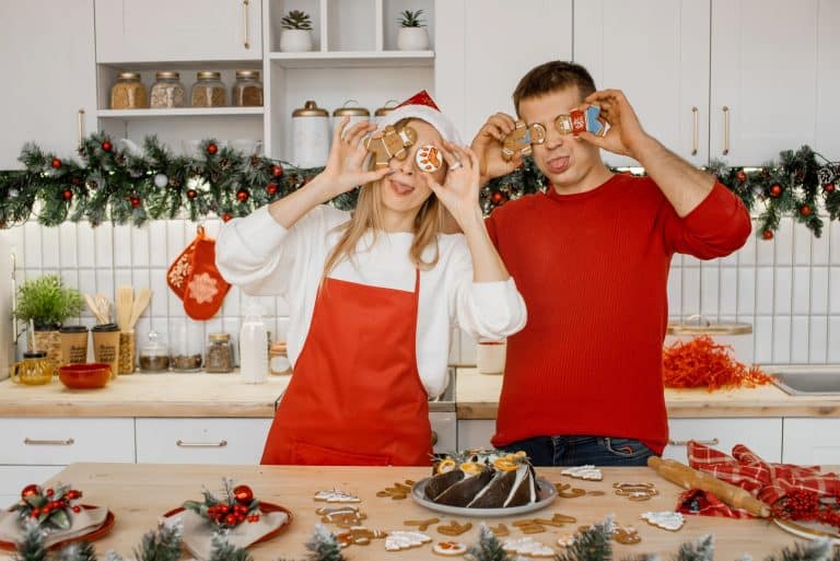 Para w białej kuchni podczas pieczenia i dekorowania świątecznych ciast i ciasteczek