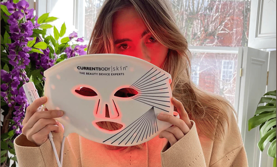 Kobieta trzymająca włączoną maskę LED CurrentBody Skin do terapii światłem