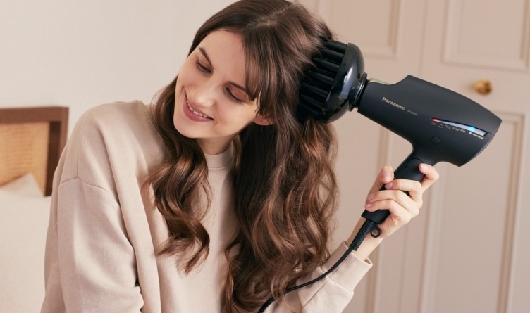 Młoda kobieta używająca suszarki do włosów Panasonic EH-NA9J z dyfuzorem