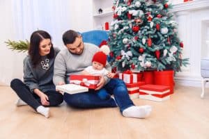 Młodzi rodzice z niemowlakiem otwierają świąteczne prezenty