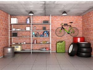 Uporządkowane wnętrze garażu z ułożonymi oponami, zawieszonym rowerem oraz narzędziami i środkami czystości na regale