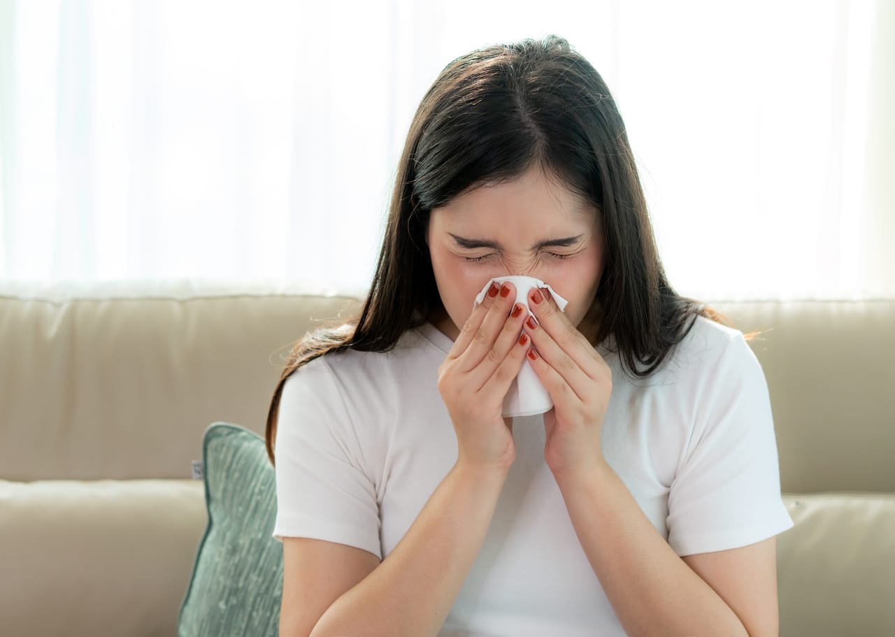 Kobieta cierpiąca na katar alergiczny spowodowany grzybem i wilgocią w domu