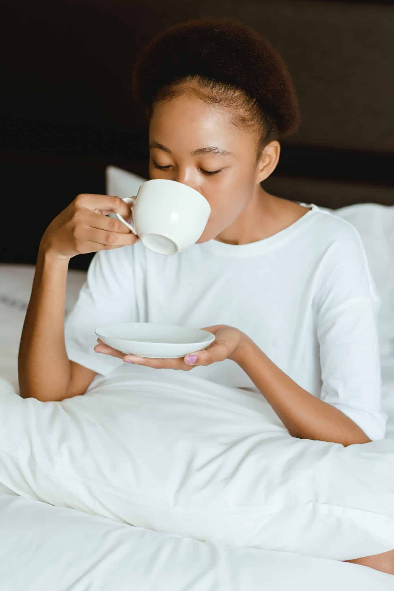 kobieta w łóżku pijąca kawę z filiżanki