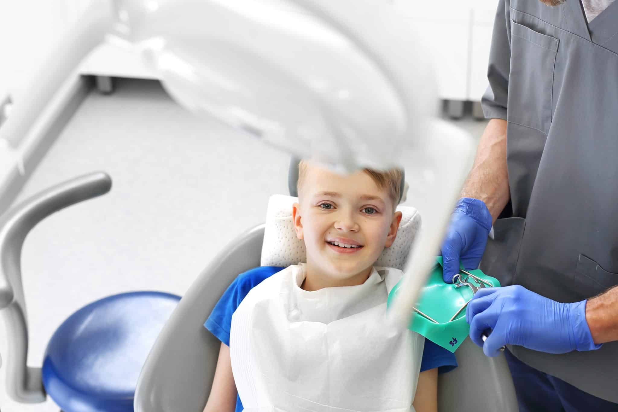uśmiechnięte dziecko na fotelu dentystycznym