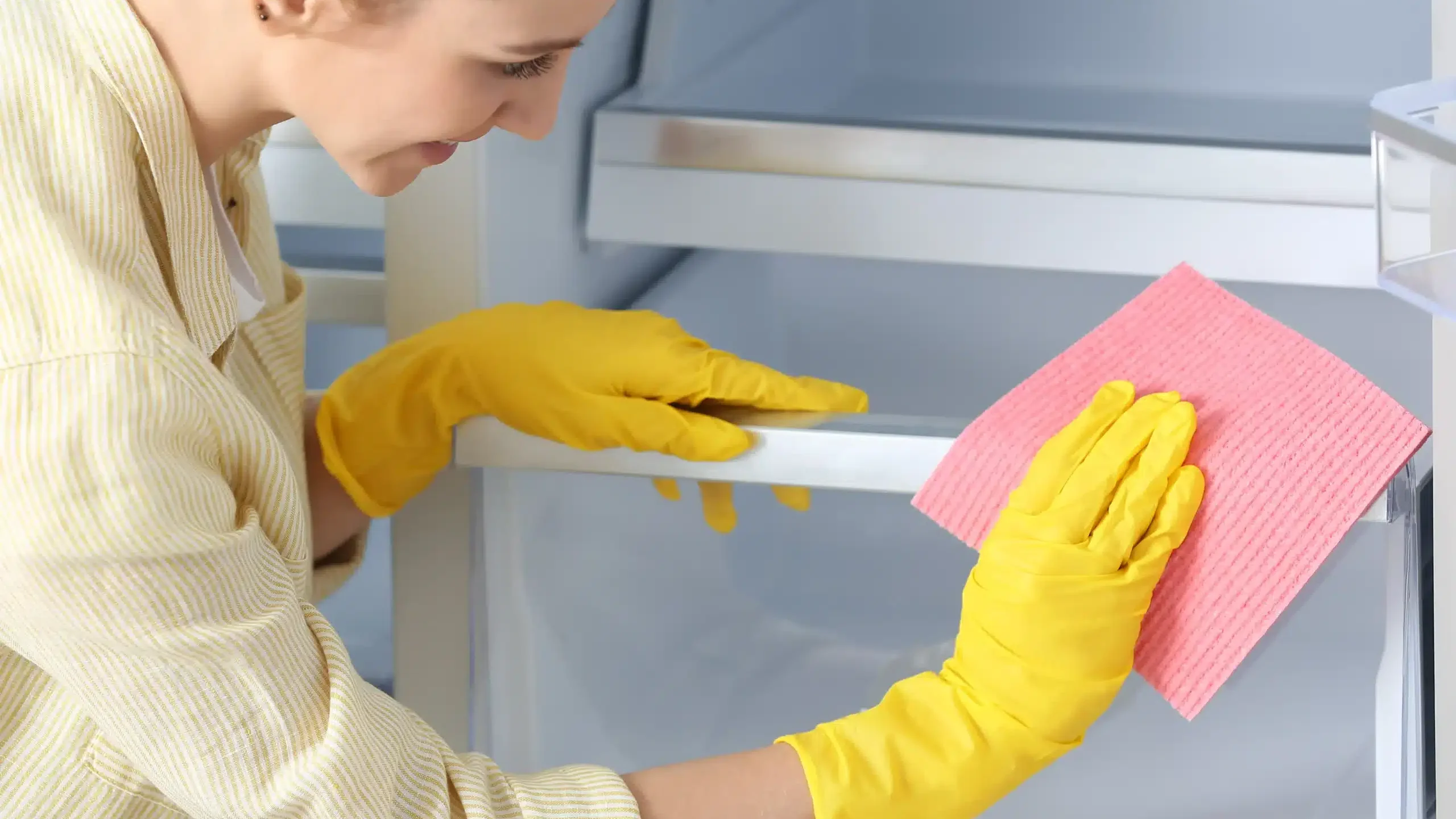Kobieta czyści lodówkę ściereczką z domowym płynem do mycia lodówki