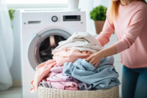 Kobieta rozpakowująca kosz na pranie przed suszeniem pościeli i ręczników w suszarce bębnowej