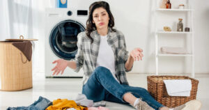 Kobieta siedzi na podłodze przed suszarką do prania A+++ i nie wie, jaki jest roczny koszt suszarki do prania