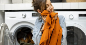 Młoda kobieta przytula do twarzy szalik wysuszony w dobrej suszarce na pranie
