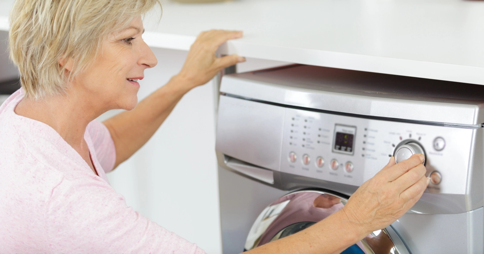 Kobieta naciska przyciski i porusza pokrętłami pralki Bosch w celu skasowania błędu e18 na wyświetlaczu