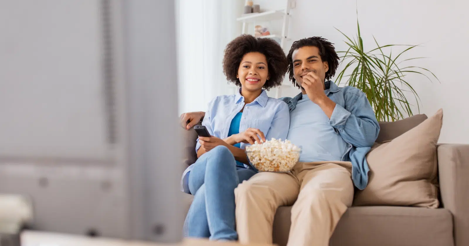 para ogląda telewizję trzymając na kolanach miskę popcornu