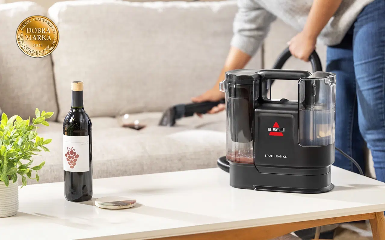 mały odkurzacz piorący do tapicerki stoi na stoliku; w te kobieta pierze tapicerkę kanapy ssawka do prania tapicerki