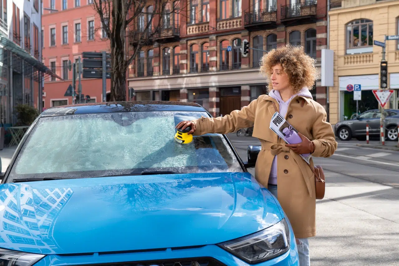 kobieta usuwa szron z samochodowej szyby przy pomocy elektrycznej skrobaczki do szyb Karcher EDI 4