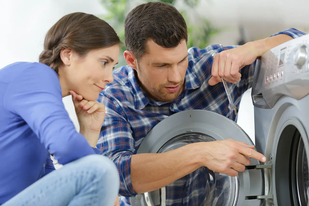 Mężczyzna i kobieta sprawdzający bęben pralki.