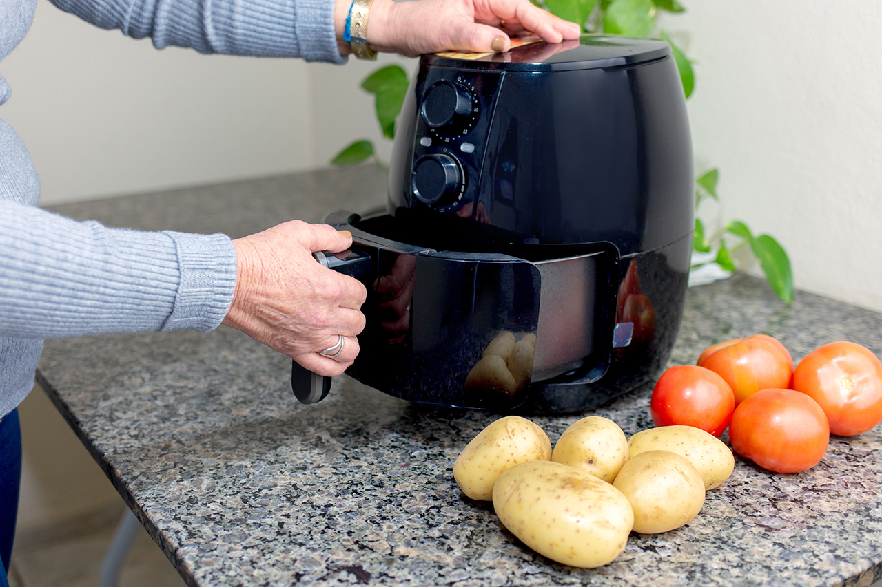 Osoba otwierająca czarny airfryer. - zdjęcie