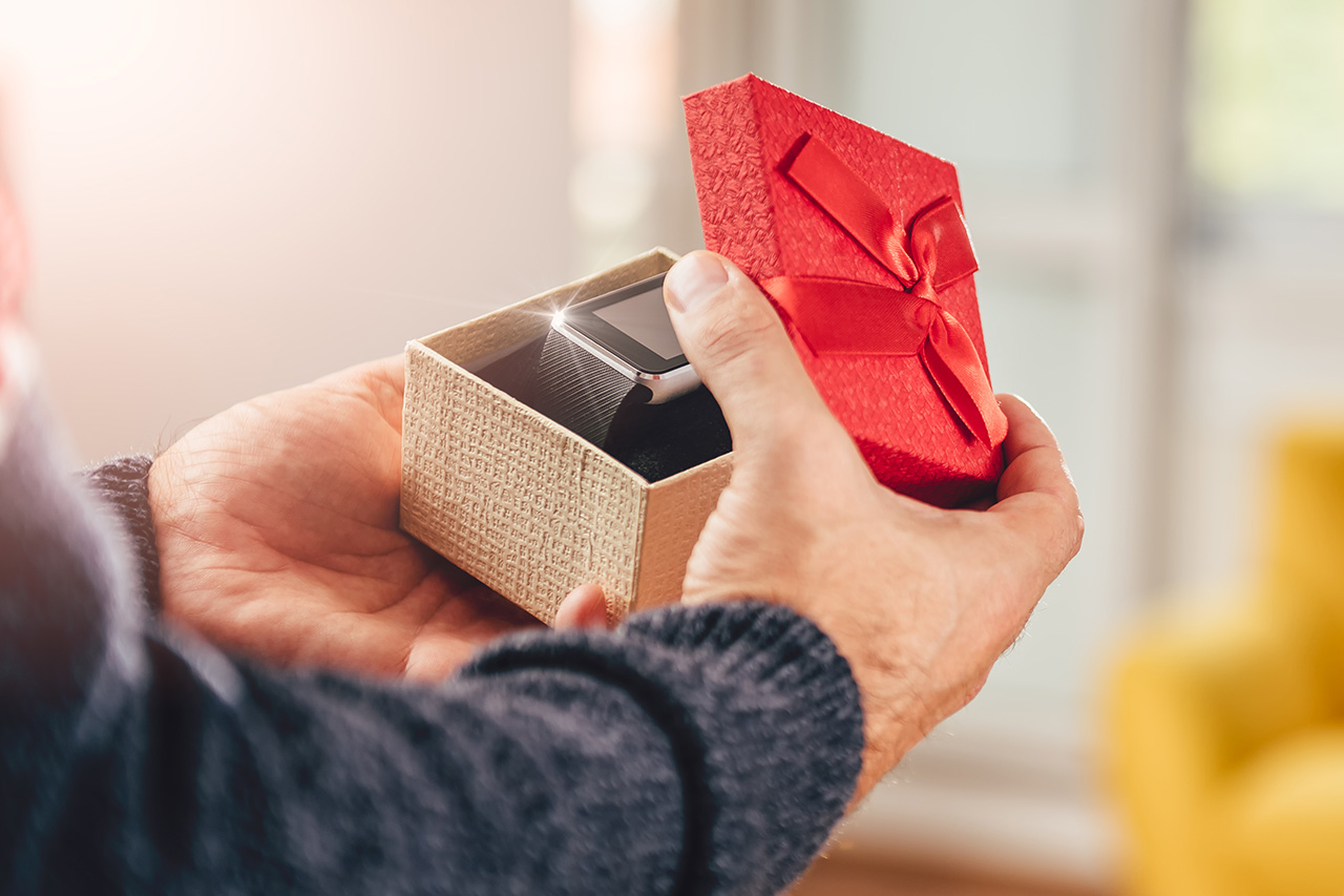 Mężczyzna otwierający pudełko prezentowe z smartwatchem - zdjęcie.
