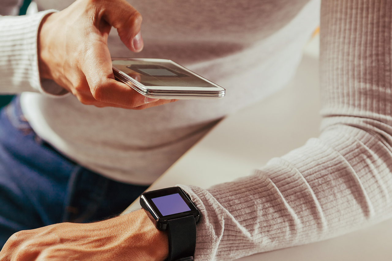 Kobieta próbująca połączyć smartphone z smartwatchem - zdjęcie